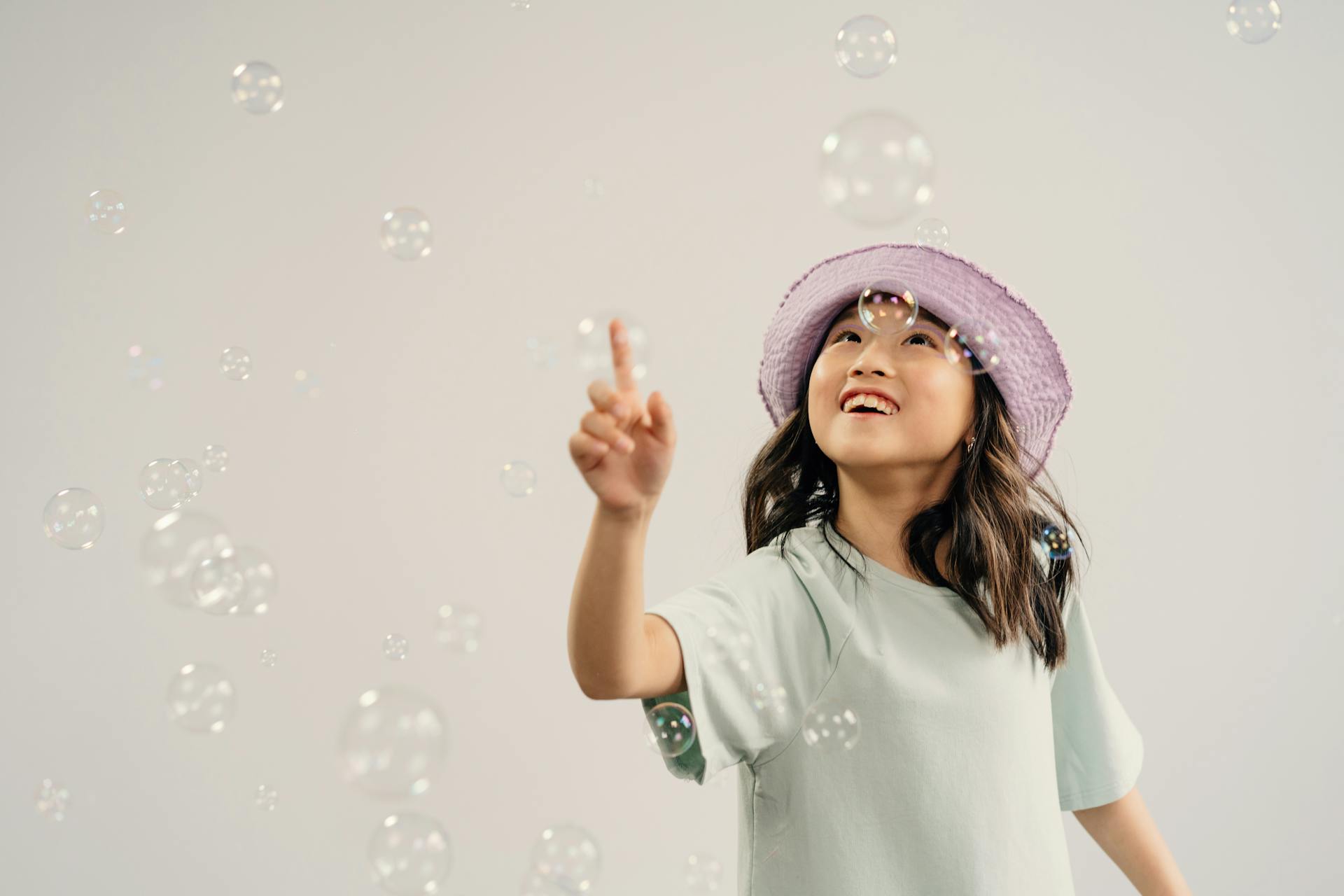 A child reaching up and smiling at floating bubbles