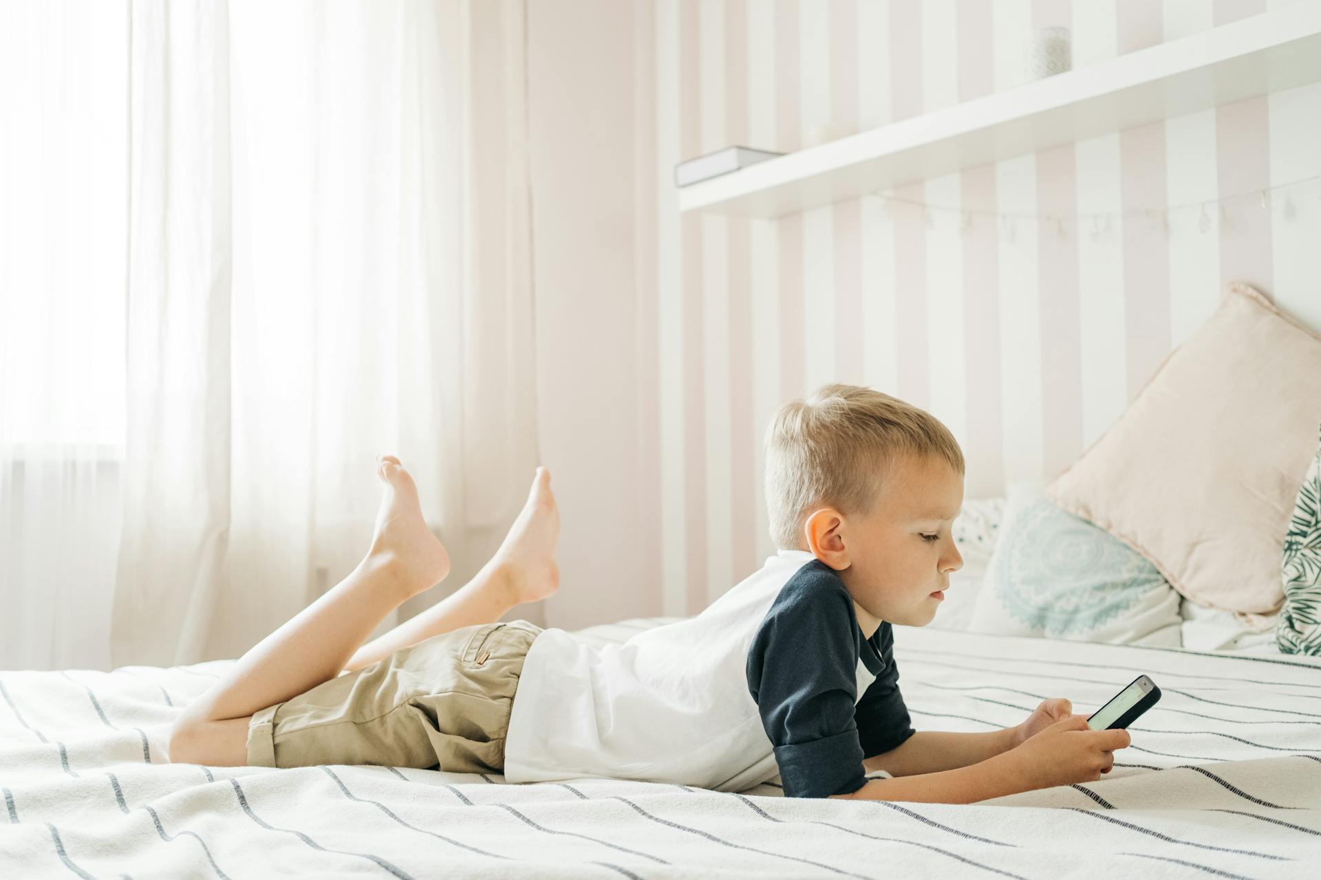 A child safely using a phone while seated on a bed